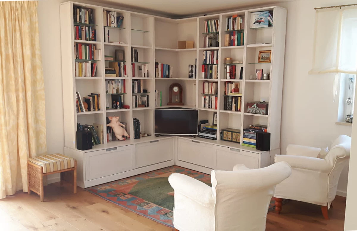 Maßgefertigtes Esche-Massivholzregal in München-Freimann Maßgefertigtes Eckregal aus massiver Esche in München-Freimann mit offenen Bücherfächern und integriertem Stauraum